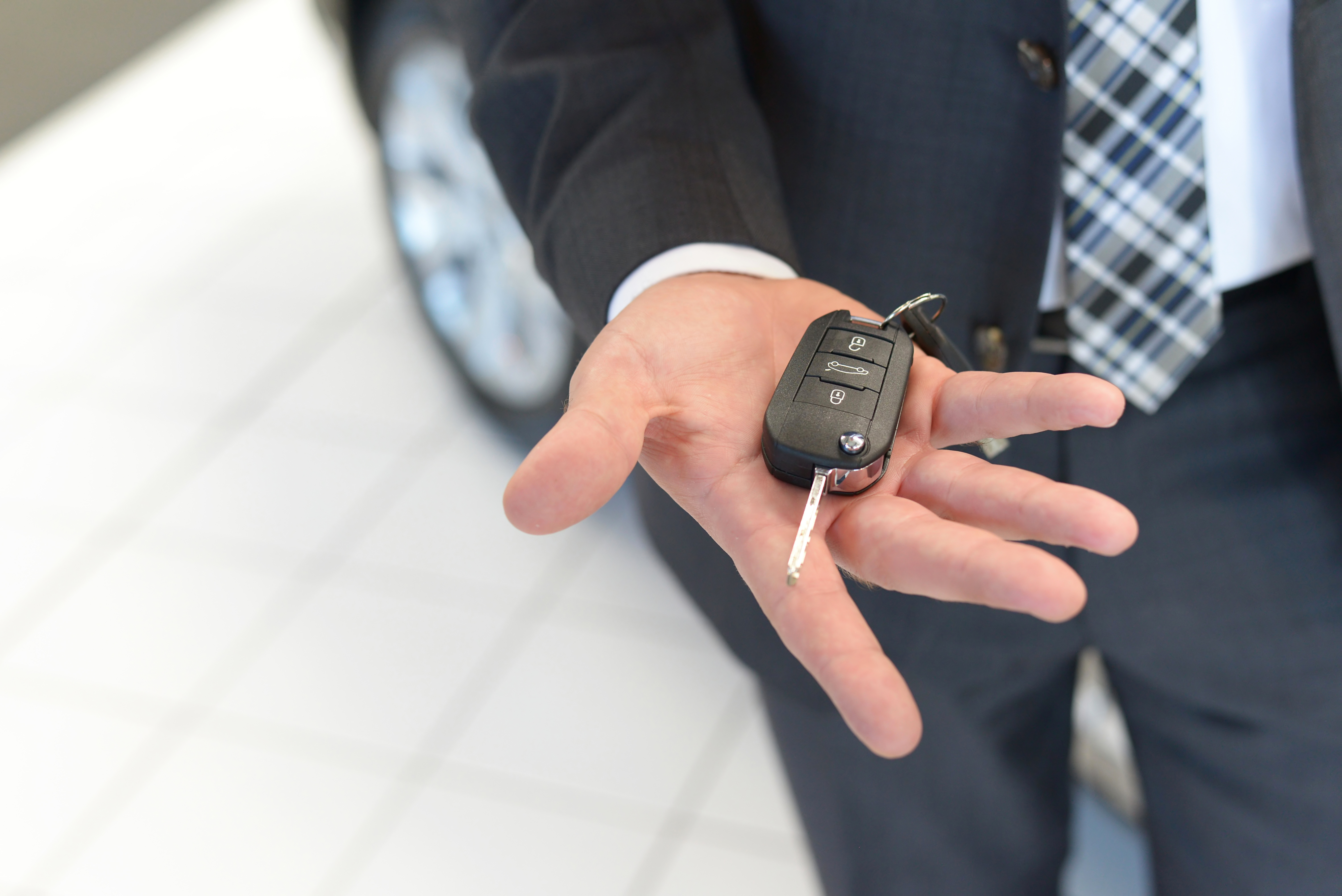 Verkufer hlt neuen Autoschlssel in der Hand